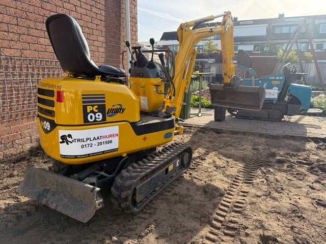 Mini-graafmachine aan het werk in achtertuin voor afgraven grond